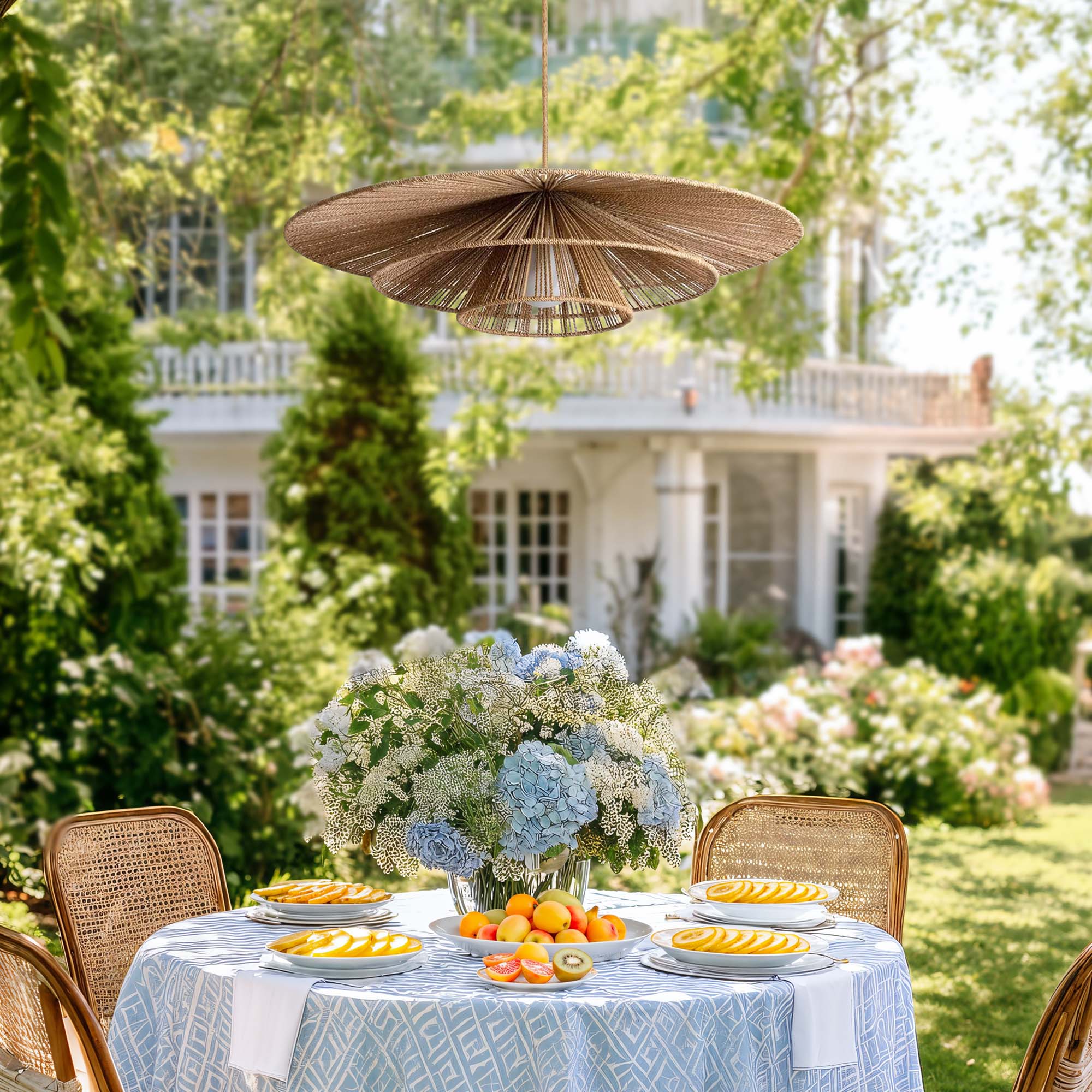 outdoor-garden-sammie-rattan-pendant-light-dining with flowers and fruit, surrounded by greenery and a house in the background.
