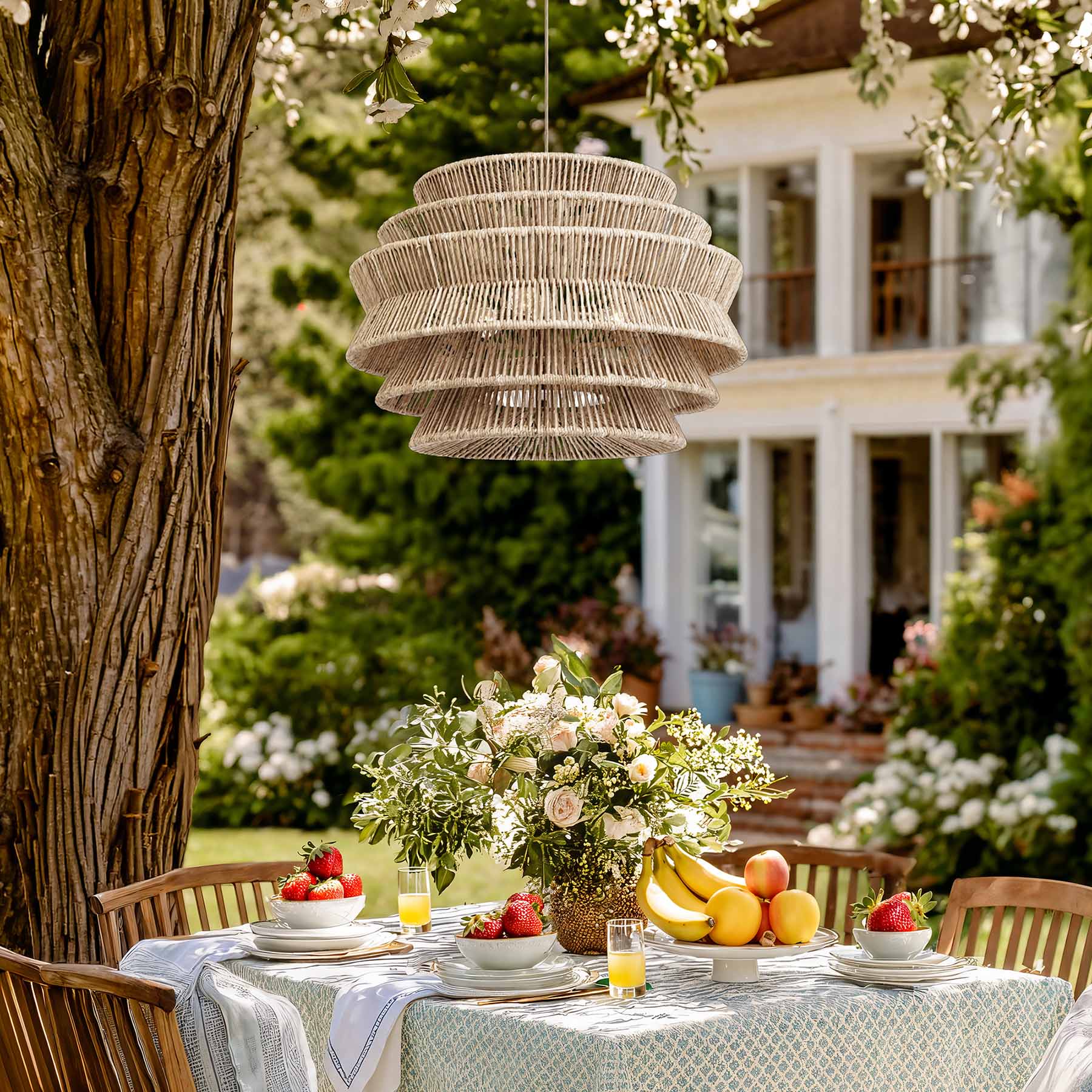 outdoor veronica rattan pendant light above a dining table in an outdoor setting with flowers